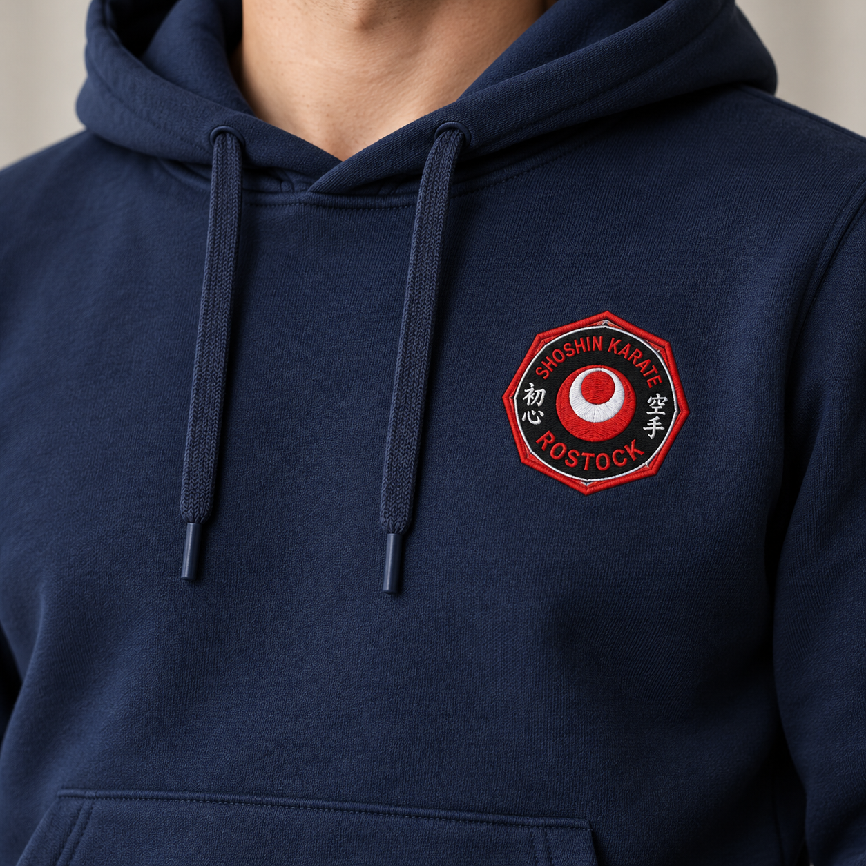  Nahaufnahme des ShoShin-Logos auf der linken Brustseite eines navyfarbenen Kapuzenpullovers