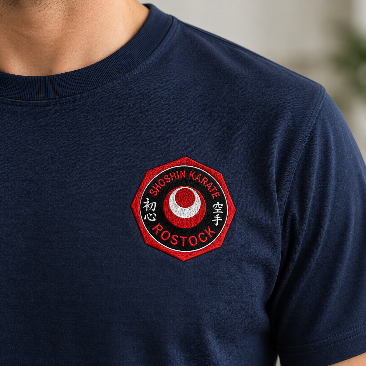 Nahaufnahme des ShoShin-Logos auf der linken Brustseite eines navyfarbenen T-Shirts